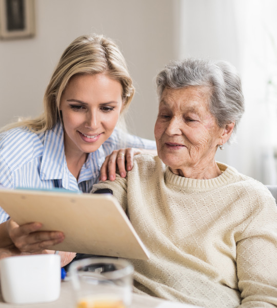 Eine Seniorin mit einer Angehörigen beim Beantragen der Kostenübernahme