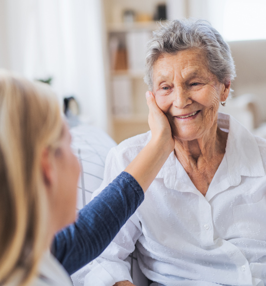 Eine lächelnde Seniorin die von einer Angehörigen gepflegt wird